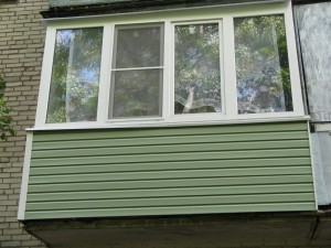 Обшивка балкона зеленым сайдингом снаружи